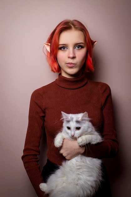 Teenage girl with pink hair holding a white cat in her arms