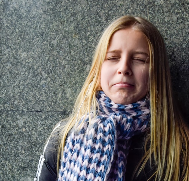 A teenage girl with a sad offended expression against the wall