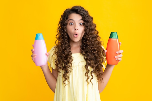 Teenage girl with shampoos conditioners or shower gel kids hair care cosmetic product shampoo bottle amazed surprised emotions of young teenager girl