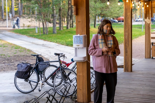 A teenage girl with a smartphone on the terrace of an outdoor cafe in the park