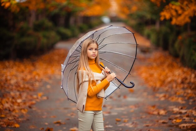 Photo teenage girl with a transparent umbrella in her hands on a walk in the autumn on a city street