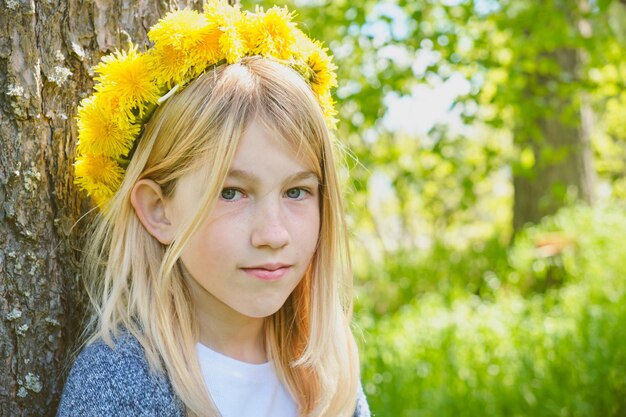 黄色いタンポポの花輪の10代の少女