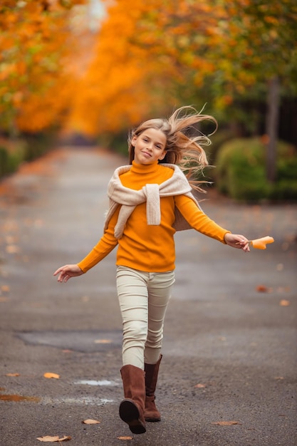 Photo a teenage girl in a yellow sweater walks along a street outside the city against the backdrop of yellow trees fun walk in autumn