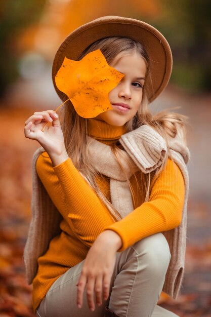 Photo a teenage girl in a yellow sweater walks along a street outside the city against the backdrop of yellow trees fun walk in autumn