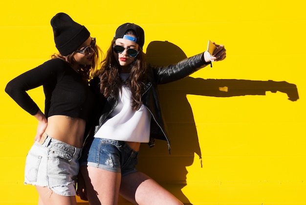 Teenage girls friends outdoors make selfie on a phone. 