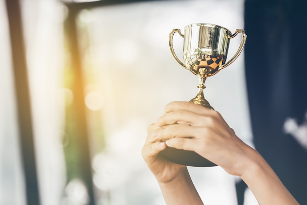 Teenage girls' hands are holding trophies congratulations on success.