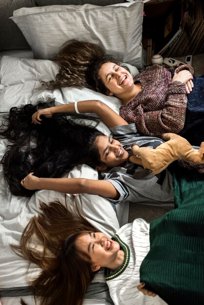 Teenage girls lying on the bed together with stuffed animal childhood and friendship concept