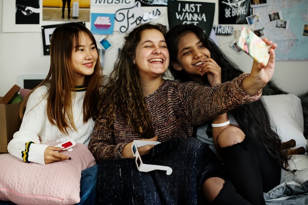 Teenage girls using a smartphone to take a selfie in a bedroom 