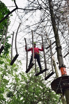 Un adolescente si arrampica su una scala sospesa in un parco di divertimenti in corda