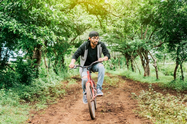 Teenage guy riding a bike in the countryside Portrait of a guy in cap riding a bike on a country road Person riding a bike in the countryside Bicyclist person on his bike on a country road forest