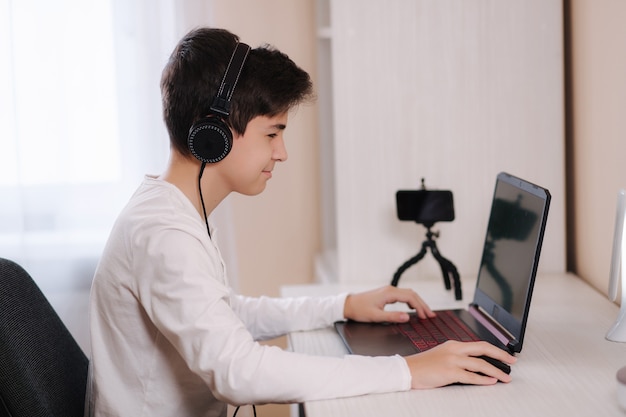 Teenage jongen speelspel op zijn pc-computer in witte kamer