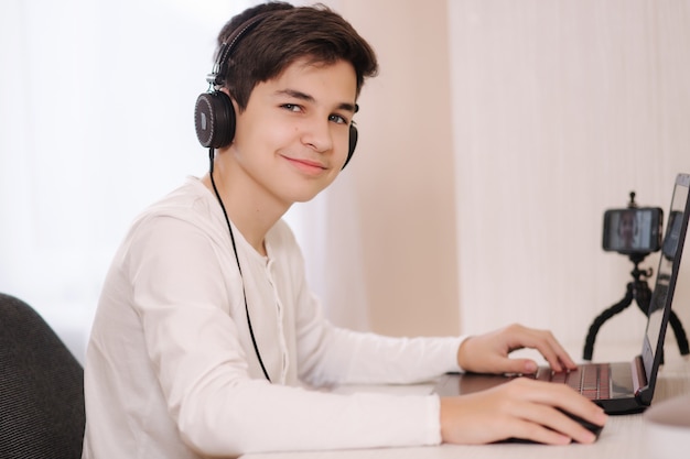 Teenage jongen speelspel op zijn pc-computer in witte kamer