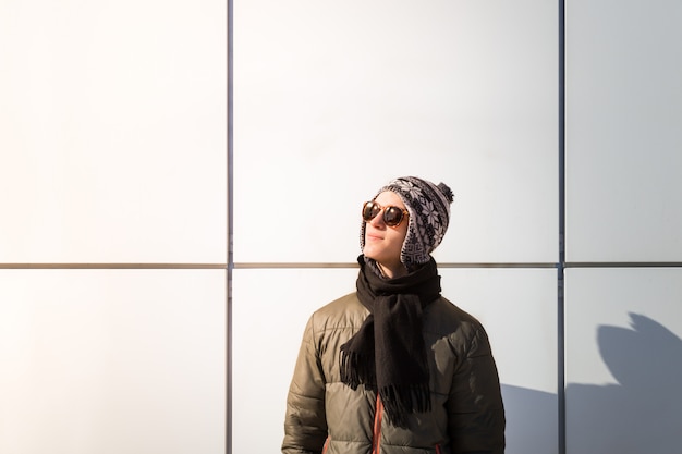 Teenage person poses near a wall