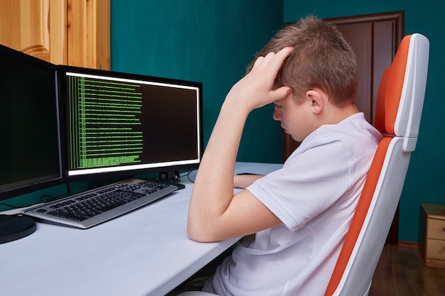 A teenage programmer thinks about the code for solving a computer problem the programming language code on the monitor screen