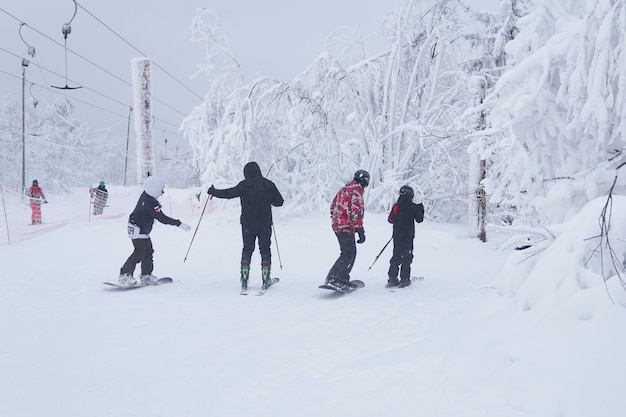 10代のスキーヤーとスノーボーダーが森の小道に沿って山を滑り降りようとしています