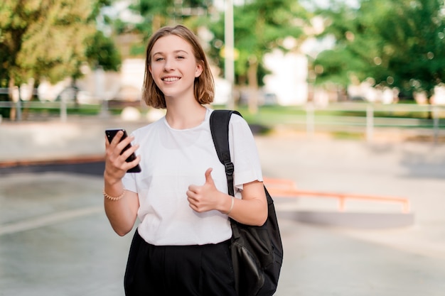 Teenage student girl with a school bag in a park