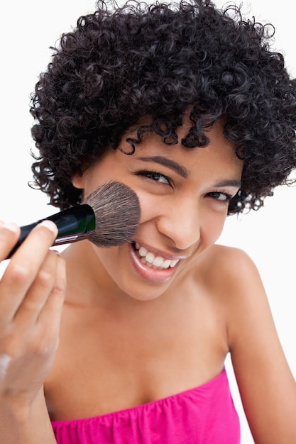 Teenage using a powder brush to apply make up