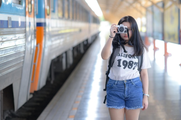 Una donna adolescente con in mano una telecamera su una piattaforma del treno