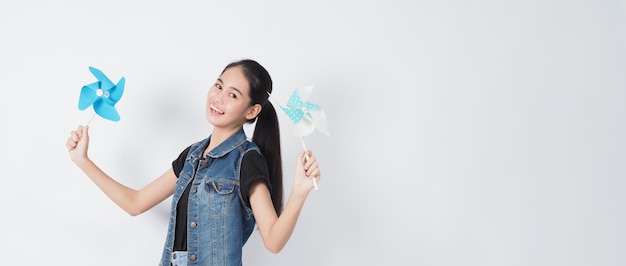 Teenage woman and paper windmill toys Portrait teen with blue color paper wind wheel wood stick