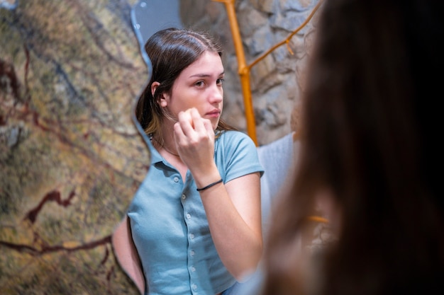 Teenage woman putting on makeup in the bathroom.