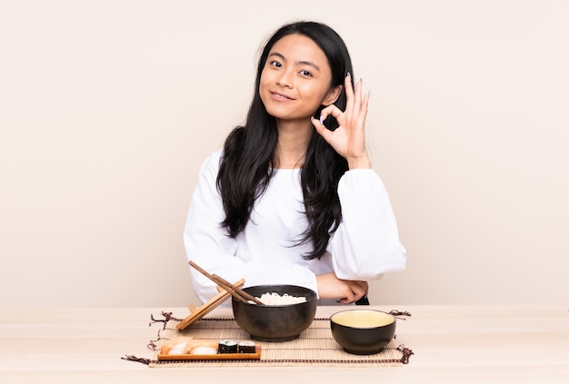 Teenager Asian girl eating asian food isolated on beige