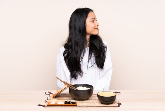 Teenager Asian girl eating asian food isolated on beige