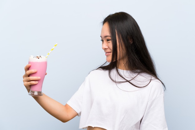 Teenager asian girl holding a strawberry milkshake with happy expression