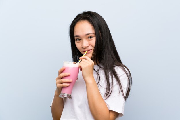 Ragazza asiatica dell'adolescente che tiene un frappé della fragola