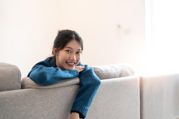 Teenager Asian woman feeling happy smiling and looking to camera while relax in living room at home