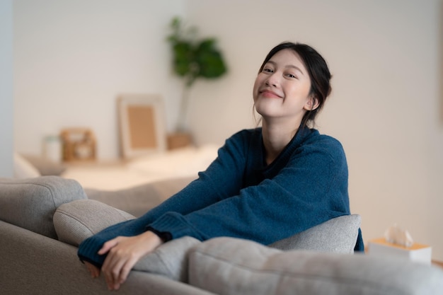 Teenager Asian woman feeling happy smiling and looking to camera while relax in living room at home