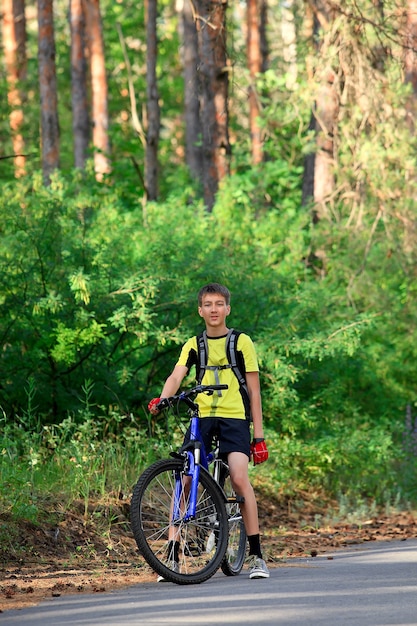 A teenager on a bicycle traveling in the forest