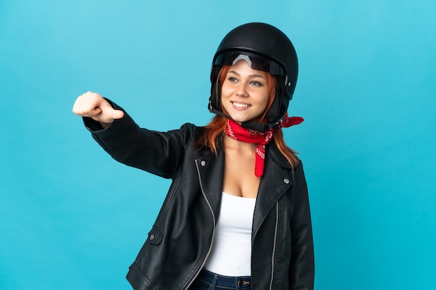 Teenager biker girl on blue giving a thumbs up gesture