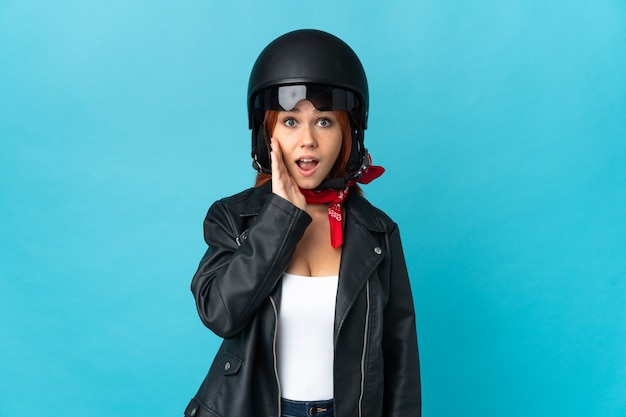 Teenager biker girl on blue with surprise and shocked facial expression