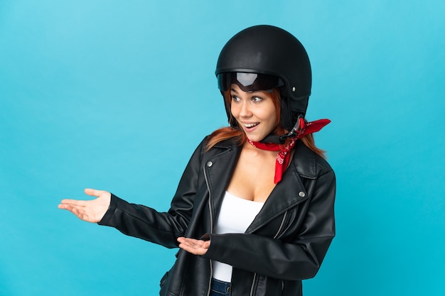 Teenager biker girl isolated on blue background with surprise expression while looking side
