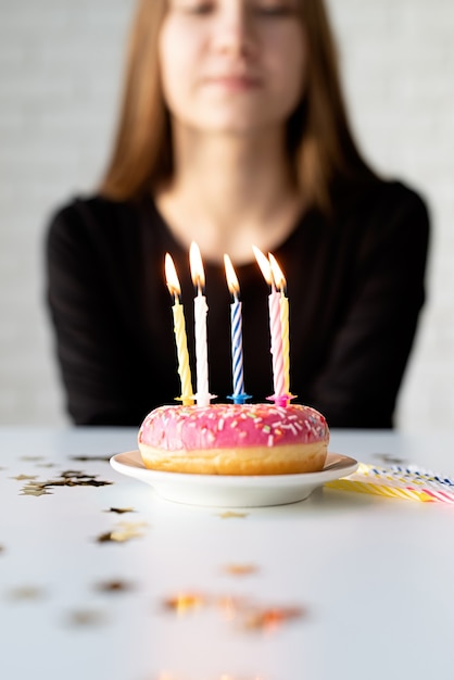 Foto ragazza di compleanno dell'adolescente che soffia candele sulla ciambella