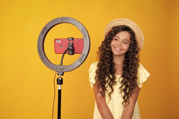 10代のブロガーがビデオを作成する子vloggerインフルエンサーの記録コンテンツ子ブロガーは、リングビデオランプを使用して携帯電話でビデオを記録します。10代の少女の幸せな10代のポジティブで笑顔の感情