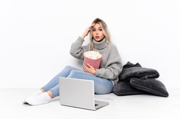 Ragazza bionda dell'adolescente che mangia popcorn mentre guarda un film