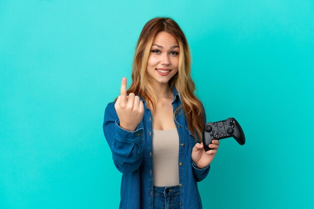 Ragazza bionda dell'adolescente che gioca con un controller per videogiochi su una parete isolata che fa un gesto imminente