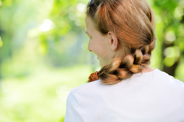 Photo teenager blonde girl with braid pigtails in nature