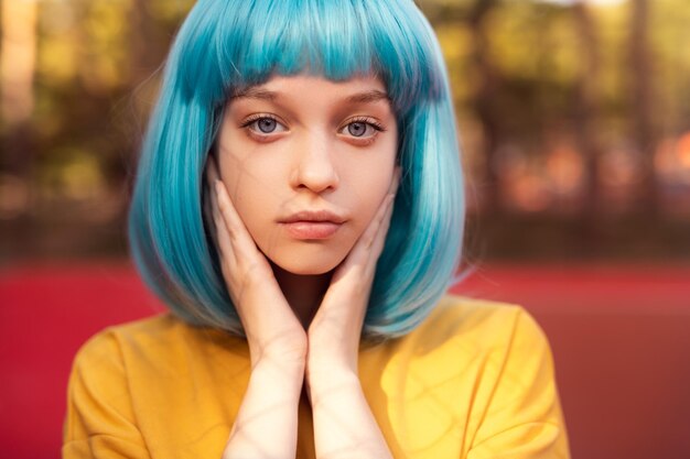 Teenager in blue wig looking at camera