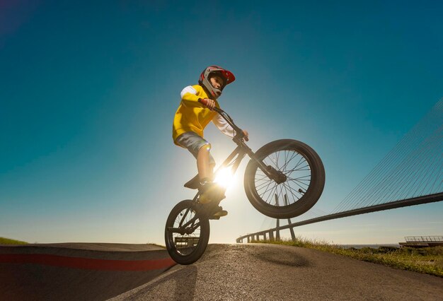 A teenager bmx racing rider performs tricks in a skate park on a pump track