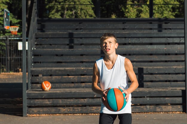 Giocatore di pallacanestro del ragazzo dell'adolescente che dribbla sul campo sportivo