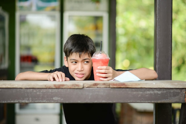 Foto ragazzo dell'adolescente che beve il succo di frutta nel periodo estivo del campeggio del parco