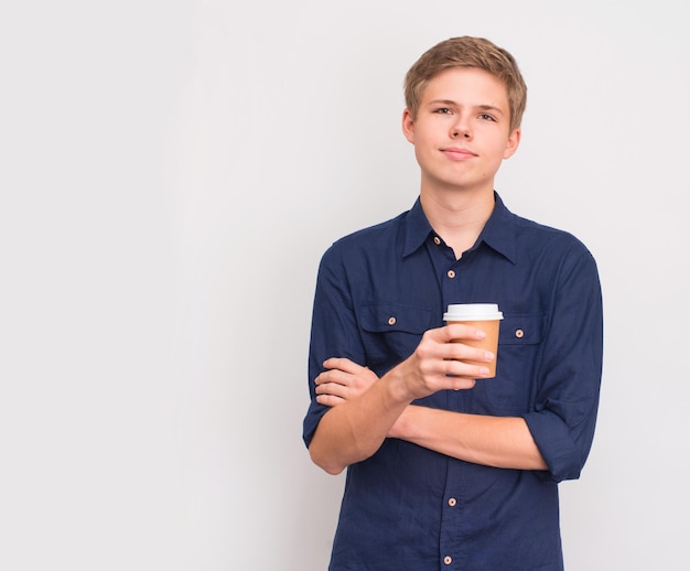 Teenager boy enjoying hot drink in disposable paper cup on light grey background with copyspace Takeaway and people concept