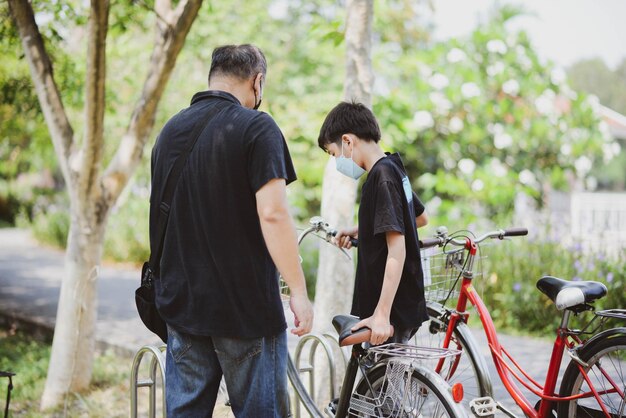 Foto bicicletta di guida del ragazzo dell'adolescente nel parco con la famiglia felice