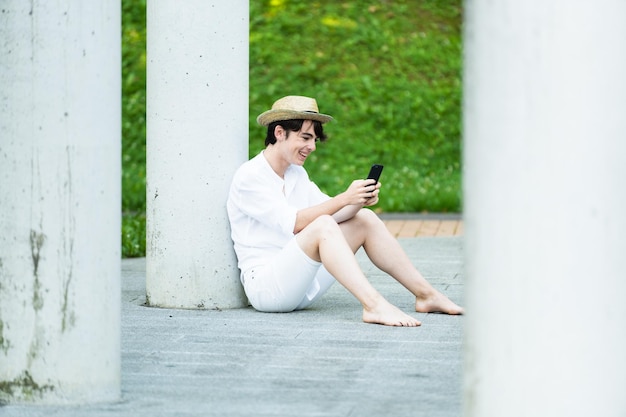 바닥에 앉아서 전화를 사용하는 십 대 소년