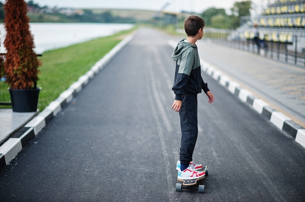 スポーツスーツを着た10代の少年がロングボードに乗る。