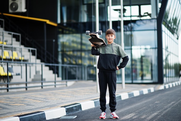 Мальчик-подросток в спортивном костюме с длинной доской