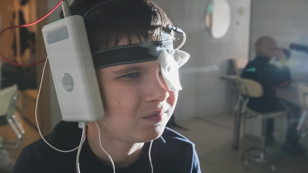 Teenager boy with electrodes on the head looking to monitor - healthcare children's diagnostic - Ophthalmology researching, close up