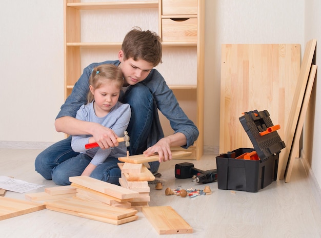 Teenager boy with his little sister assembling furniture at home